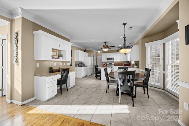 tiled dining space with ornamental molding, ceiling fan, and built in desk