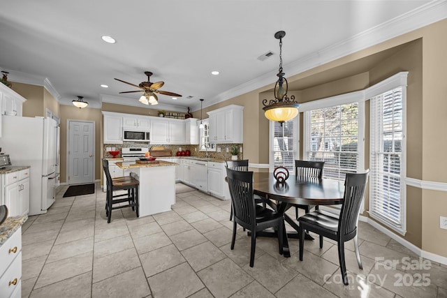 dining area with sink, crown molding, ceiling fan, and light tile patterned floors