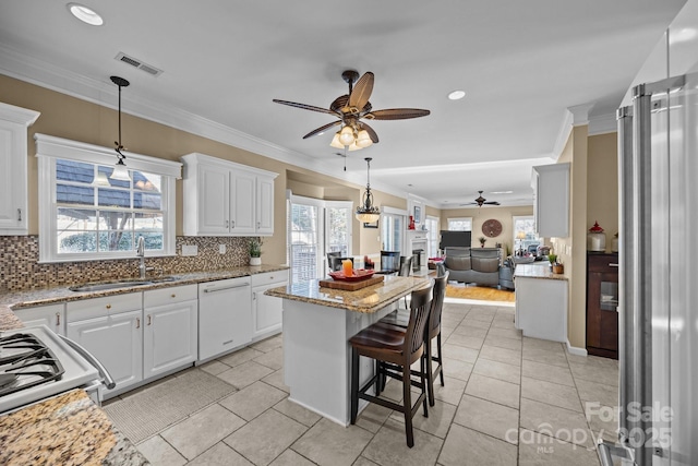 kitchen featuring sink, white cabinetry, a kitchen bar, and white appliances