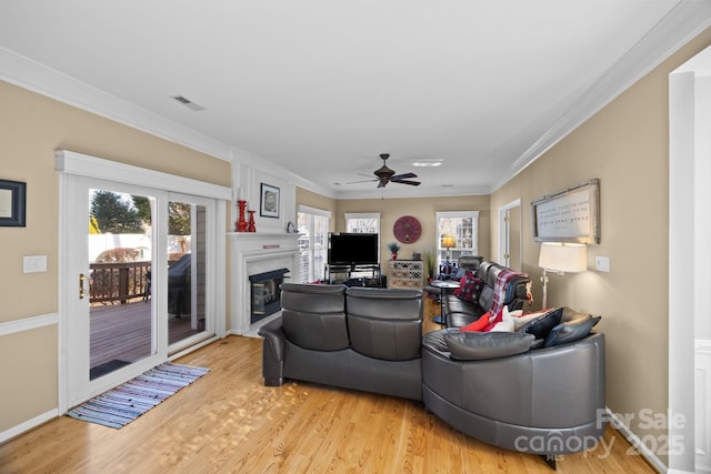 living room with ornamental molding, a large fireplace, and light wood-type flooring