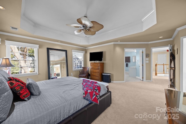 carpeted bedroom with a raised ceiling, ceiling fan, ensuite bath, and crown molding