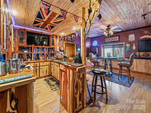 bar with a bar, wooden ceiling, wood finished floors, and a ceiling fan