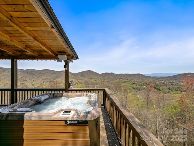 wooden deck featuring a hot tub and a mountain view