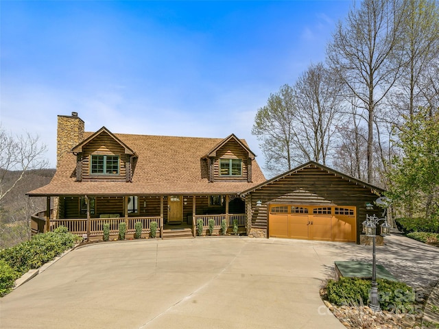 log cabin with an attached garage, covered porch, driveway, log exterior, and a chimney