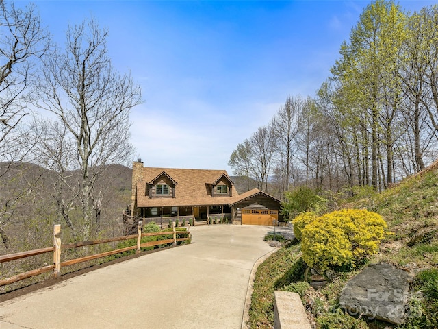 view of front of property featuring a chimney, fence, and concrete driveway