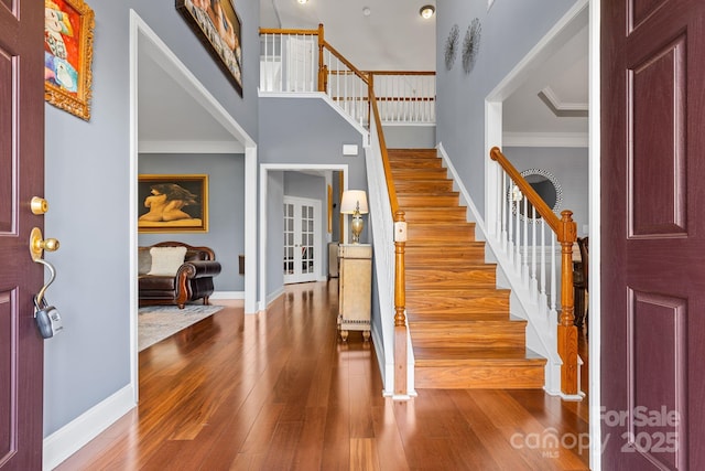 entrance foyer with ornamental molding, a high ceiling, and hardwood / wood-style floors