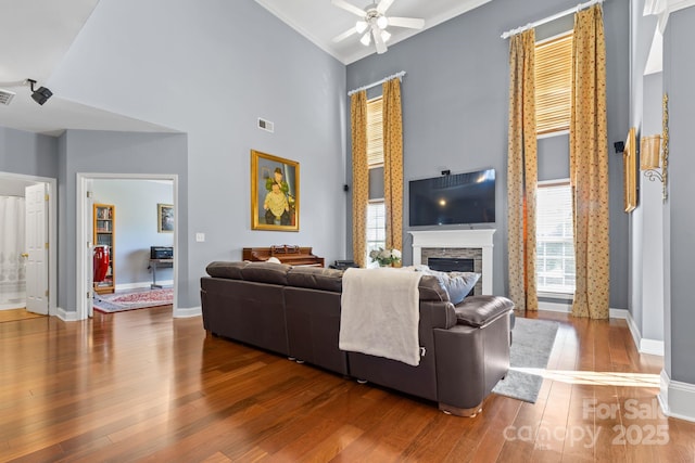 living room with hardwood / wood-style flooring, high vaulted ceiling, ceiling fan, and a fireplace