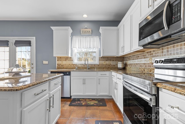 kitchen with stainless steel appliances, sink, tasteful backsplash, dark stone countertops, and white cabinets