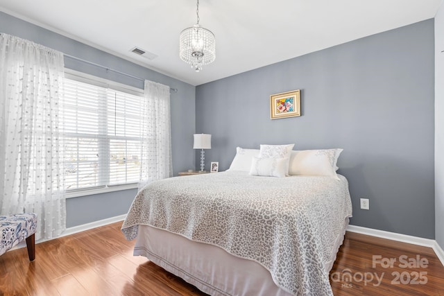 bedroom featuring an inviting chandelier and wood-type flooring