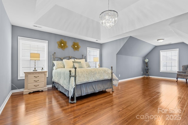 bedroom with vaulted ceiling, hardwood / wood-style floors, and an inviting chandelier