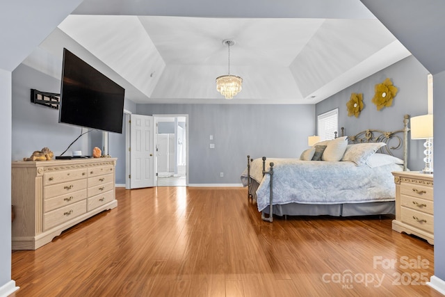 bedroom featuring a tray ceiling, a chandelier, and light hardwood / wood-style flooring