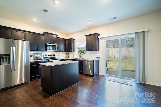 kitchen with a kitchen island, visible vents, dark brown cabinets, appliances with stainless steel finishes, and dark wood finished floors