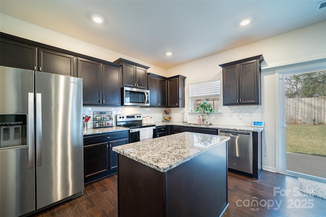 kitchen featuring light stone countertops, appliances with stainless steel finishes, dark wood-style flooring, and backsplash