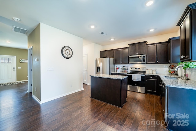 kitchen featuring visible vents, dark wood-style floors, appliances with stainless steel finishes, light stone counters, and a sink