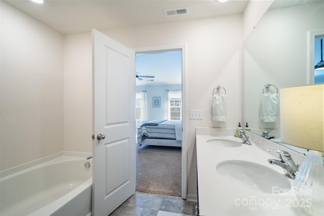 ensuite bathroom with connected bathroom, visible vents, a sink, and a bathing tub