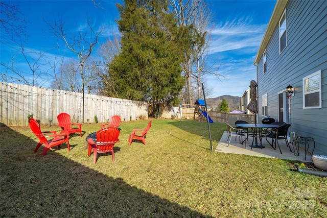 view of yard with a fenced backyard, a patio, and a playground