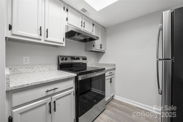 kitchen with visible vents, under cabinet range hood, stainless steel appliances, light wood-style floors, and baseboards