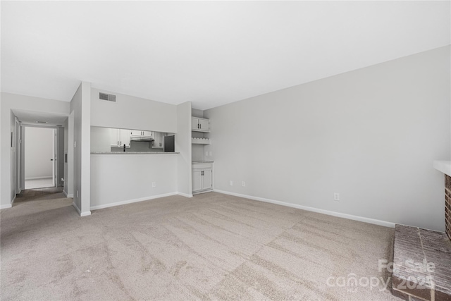 unfurnished living room featuring baseboards, visible vents, and light carpet