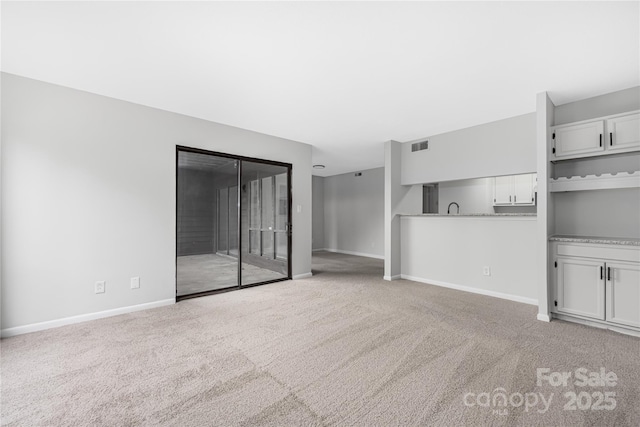 unfurnished living room with visible vents, light colored carpet, and baseboards