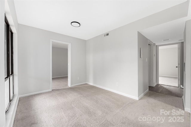 carpeted empty room with visible vents and baseboards