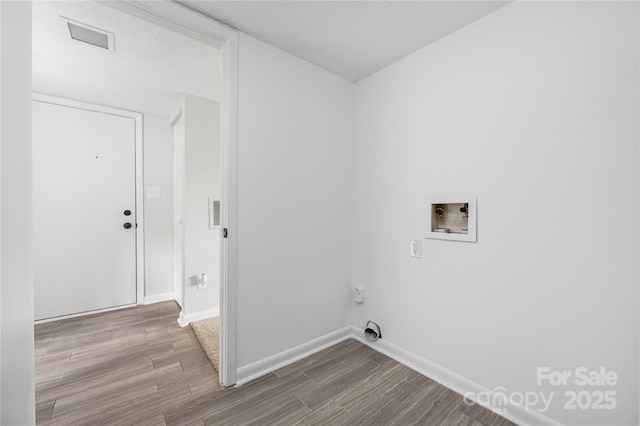 laundry area with visible vents, a textured ceiling, wood finished floors, baseboards, and laundry area