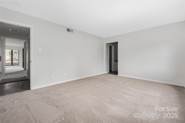 carpeted spare room featuring baseboards and visible vents