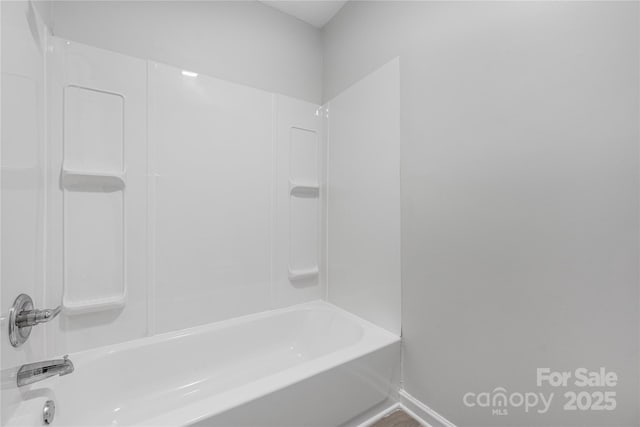 bathroom featuring bathtub / shower combination and baseboards