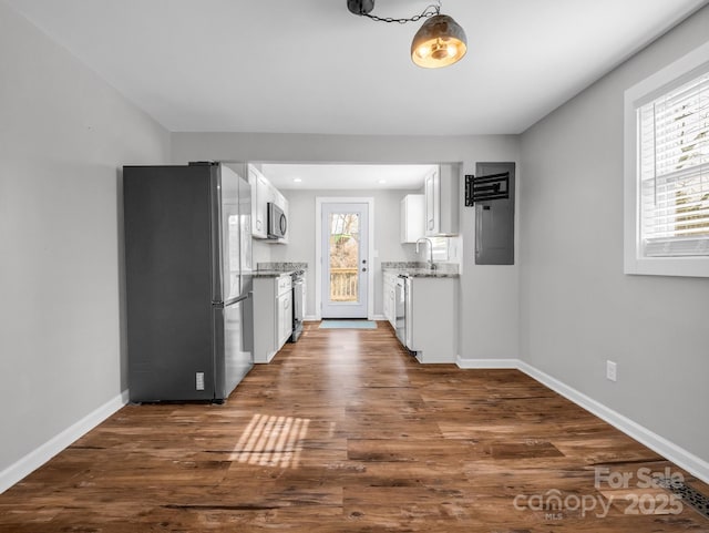 kitchen featuring light stone counters, dark wood-style floors, stainless steel appliances, white cabinetry, and baseboards