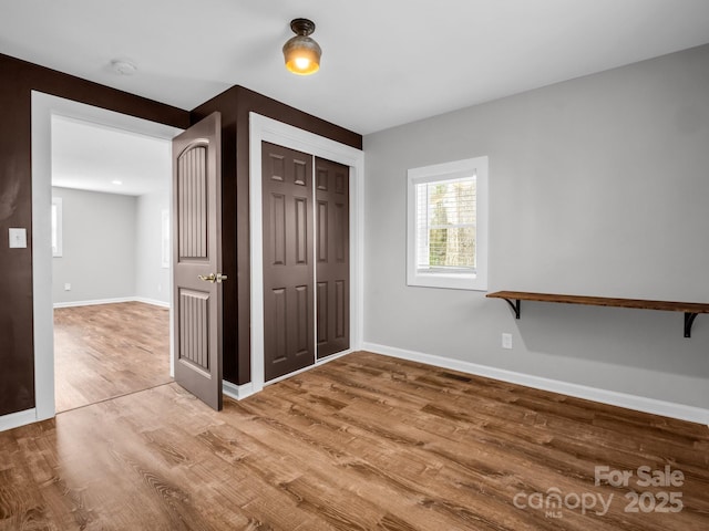 unfurnished bedroom featuring a closet, wood finished floors, and baseboards