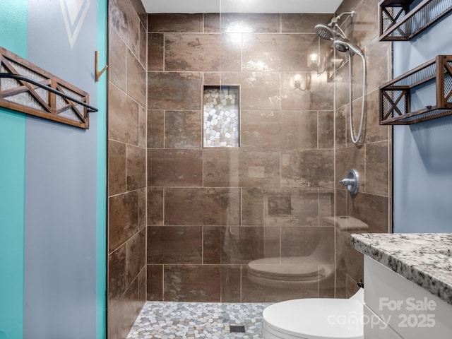 full bathroom featuring toilet, a tile shower, and vanity