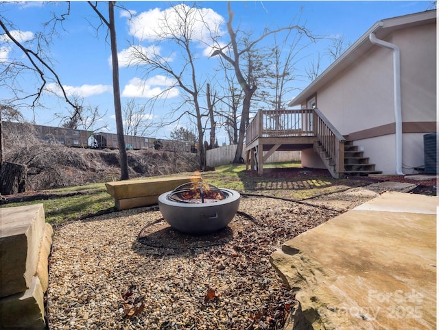 view of yard with an outdoor fire pit, fence, a wooden deck, and stairs