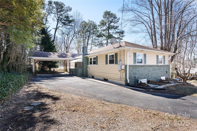 view of front of house with aphalt driveway, a chimney, and brick siding