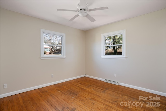 spare room with visible vents, wood-type flooring, a wealth of natural light, and baseboards