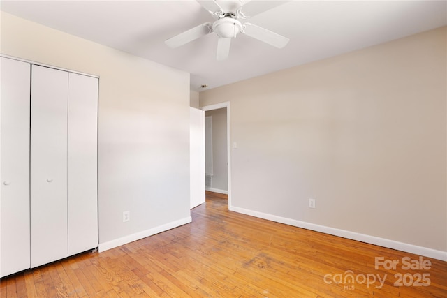 unfurnished bedroom with light wood-style flooring, baseboards, ceiling fan, and a closet