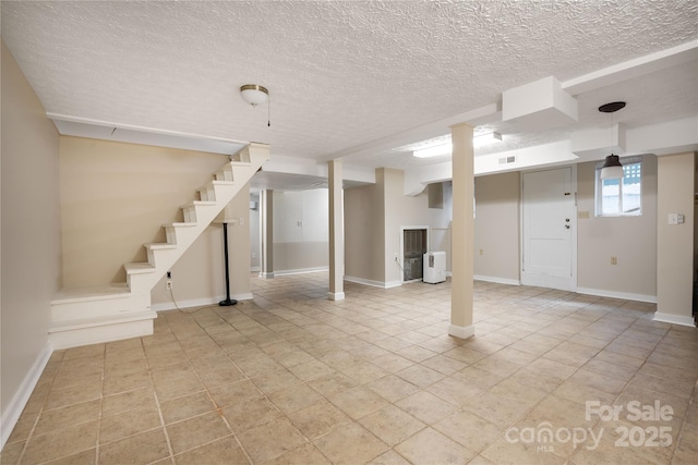 below grade area featuring baseboards, stairway, and a textured ceiling