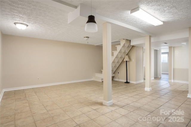 finished basement with baseboards, stairway, a textured ceiling, and light tile patterned flooring