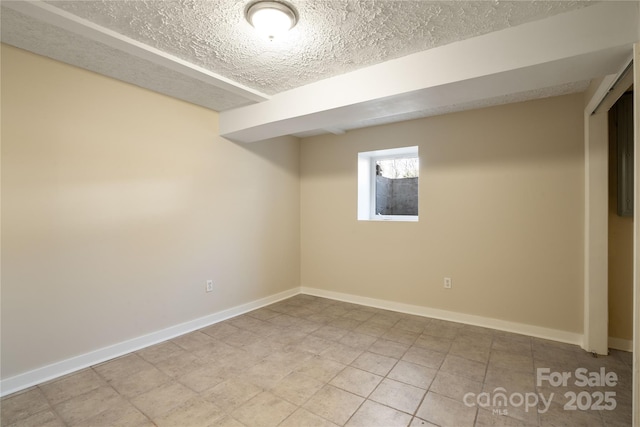 spare room featuring a textured ceiling and baseboards