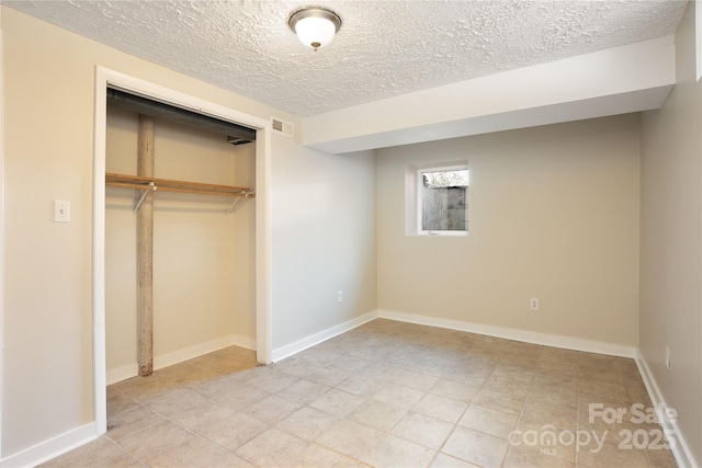 unfurnished bedroom with baseboards, a textured ceiling, visible vents, and a closet