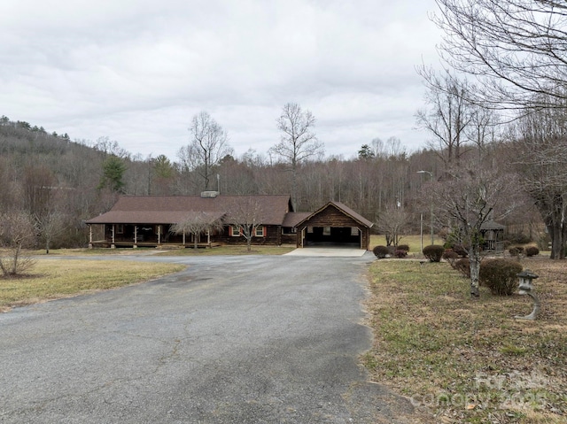 view of front facade featuring driveway and a view of trees