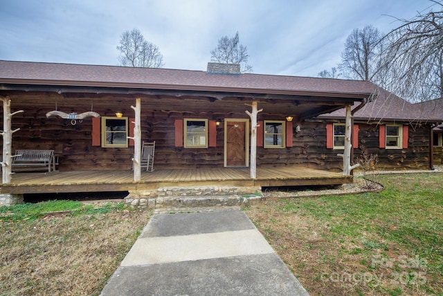 view of front of house featuring a shingled roof, a chimney, and a front lawn