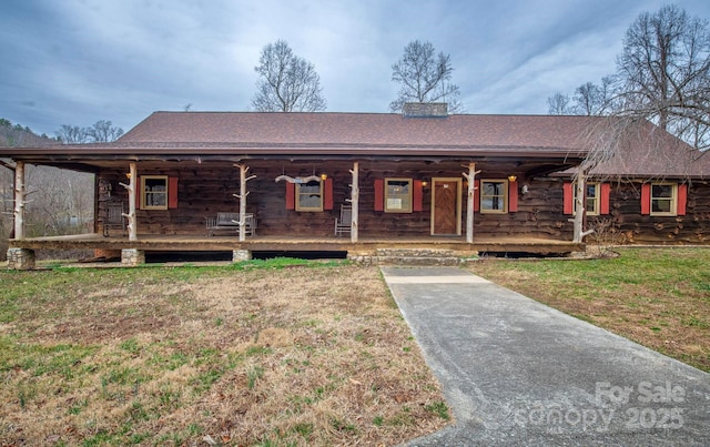 view of front of house featuring covered porch, a front lawn, a chimney, and a shingled roof