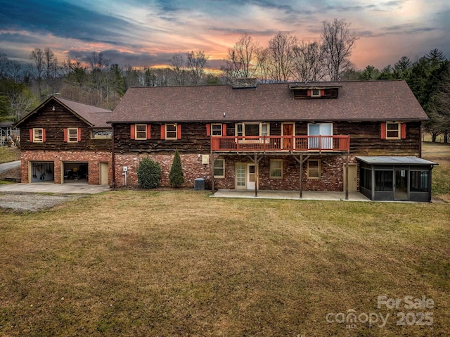 back of property at dusk with a deck, central AC, a lawn, and a sunroom