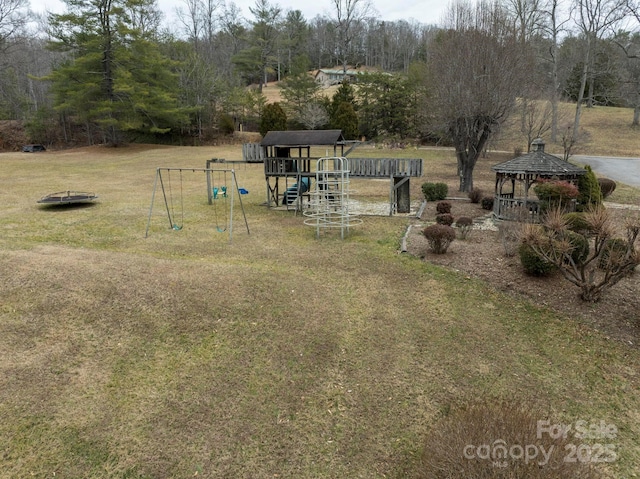 view of yard featuring playground community, a wooded view, and a gazebo