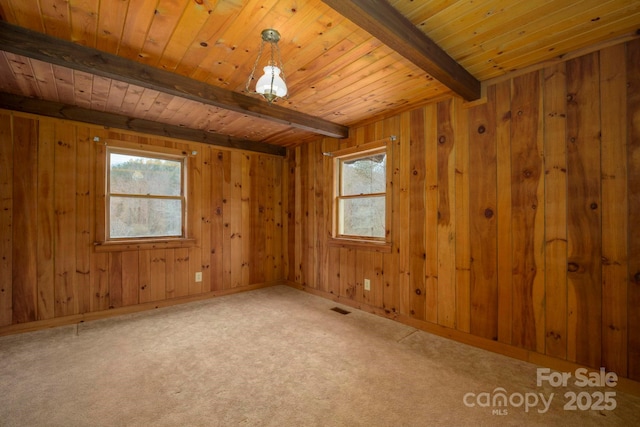 carpeted empty room featuring visible vents, wood ceiling, beamed ceiling, and a wealth of natural light