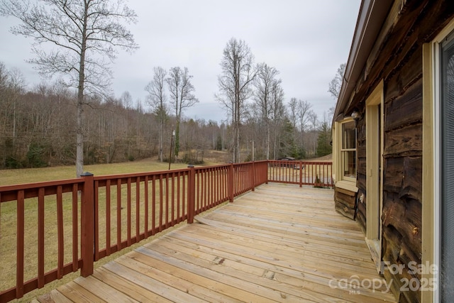 deck featuring a lawn and a forest view