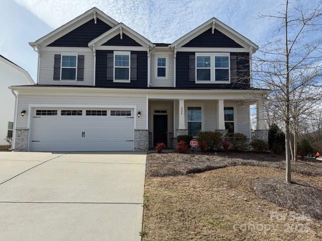 craftsman-style home with a garage, concrete driveway, a porch, and stone siding