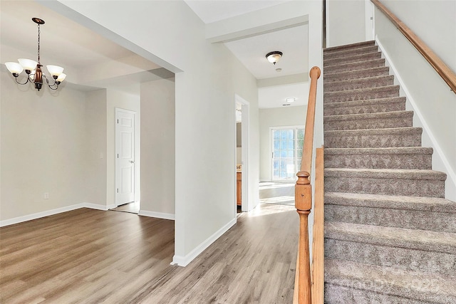 stairs with hardwood / wood-style flooring and an inviting chandelier