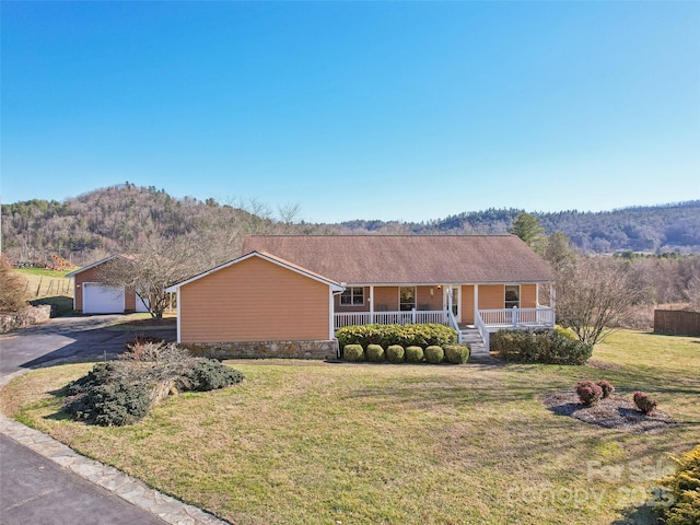 ranch-style house with a mountain view, an outbuilding, a porch, a garage, and a front yard