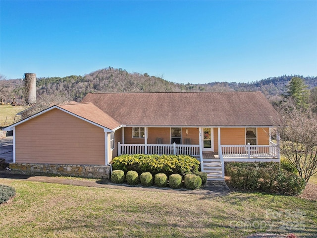 ranch-style home featuring a mountain view, a front lawn, and a porch