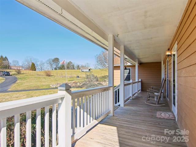 wooden deck with a rural view, a yard, and a porch